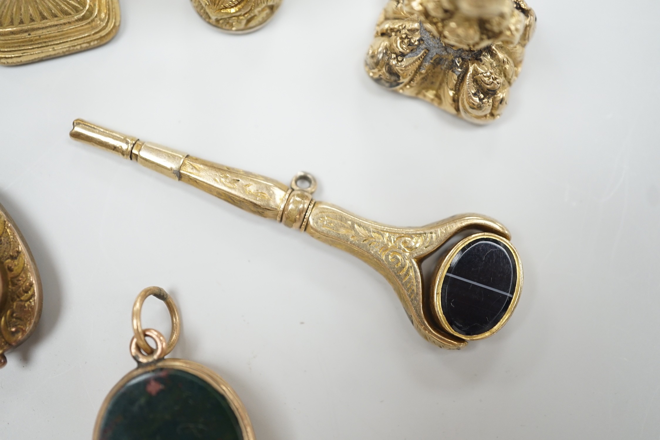 Four assorted 19th century and later yellow metal overlaid and gem set fob seals, a Victorian 15ct gold and sardonyx spinning fob, a sardonyx set locket, damaged pendant and yellow metal and two stone set watch key.